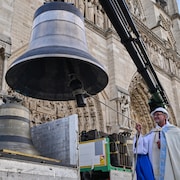 Une personne tire la corde de la cloche et sourit. 