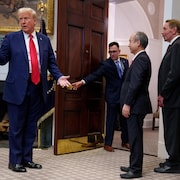 Donald Trump debout en compagnie de quatre hommes dans une salle de la Maison-Blanche.