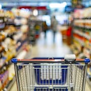 Un panier de supermarché dans une allée d'épicerie.