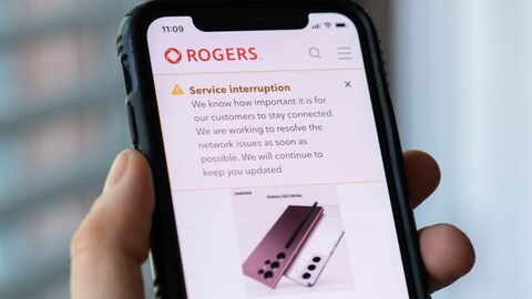 A person looks at a cell phone displaying a Rogers service interruption alert in Montreal on Friday, July 8, 2022. The outage lasted 15 hours and affected 12 million people. 