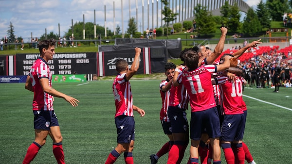 Des joueurs de soccer se sautent dans les bras après avoir marqué un but pendant un match.