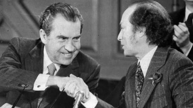 Richard Nixon and Pierre Trudeau smile as they shake hands.