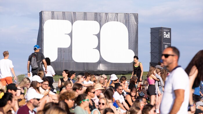 Un très gros logo du Festival d'été derrière une foule. 