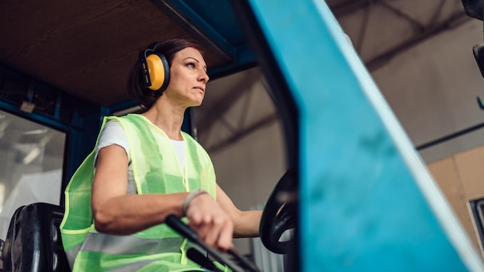 Photo en contre plongée d'une femme qui conduit un véhicule industriel.