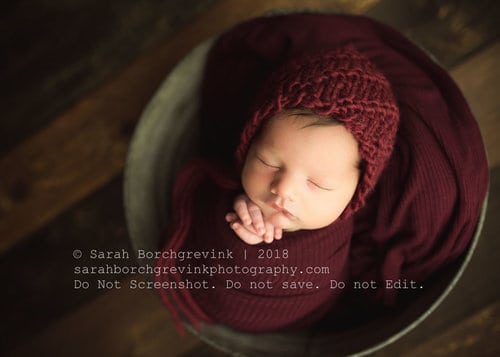 baby boy swaddled inside grey bucket