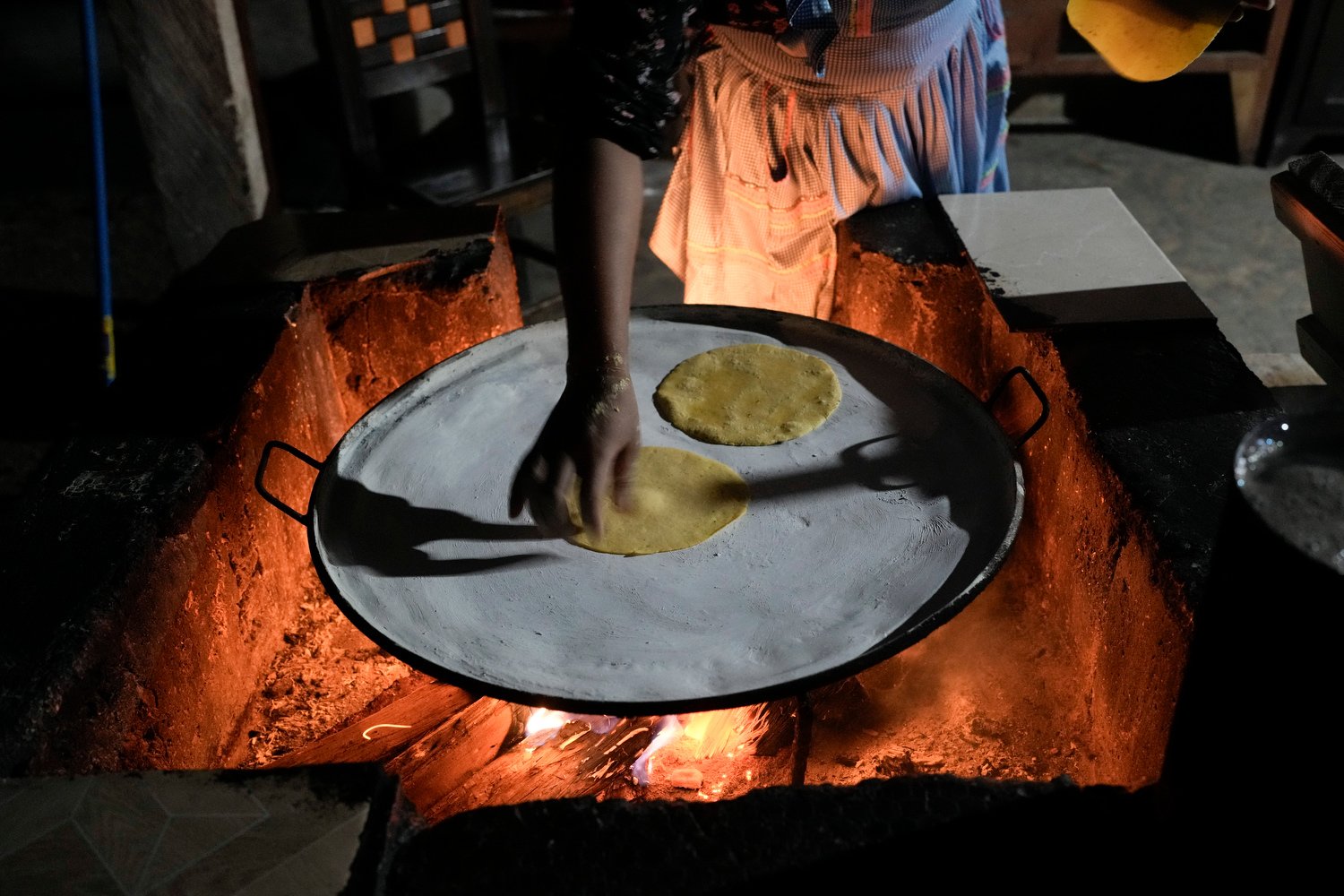   A young woman cooks tortillas over a fire in her kitchen in Plan de Ayala, a Tojolabal village in the Las Margaritas municipality of Chiapas state, Mexico, May 2, 2024. (AP Photo/Marco Ugarte) 