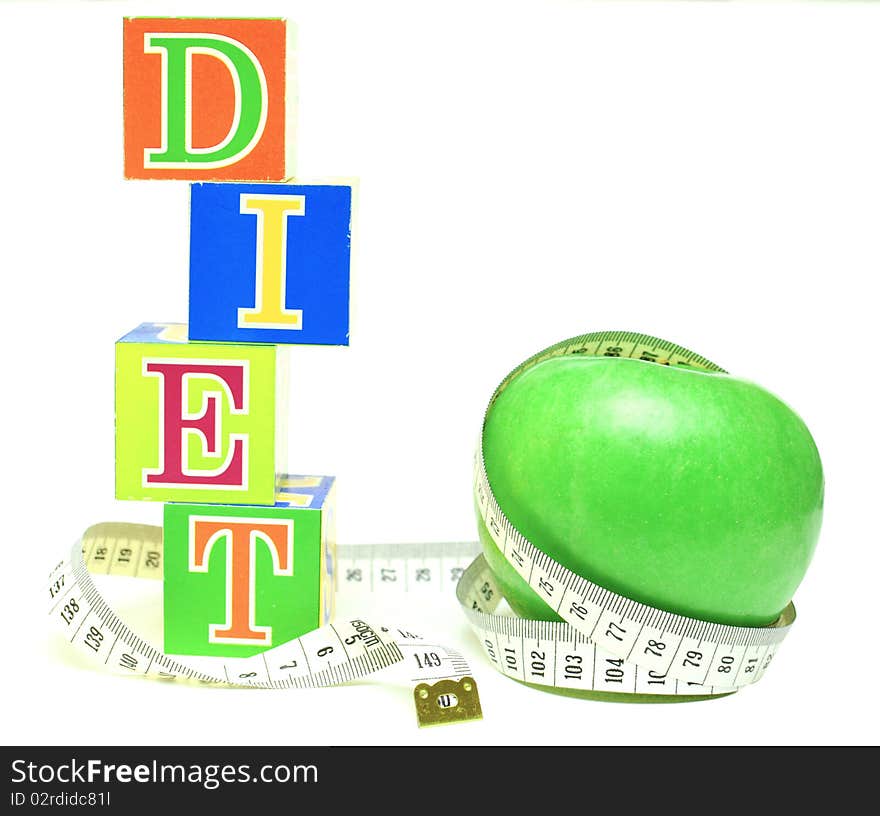 Tape measure wrapped around green apple and cubes with letters - diet