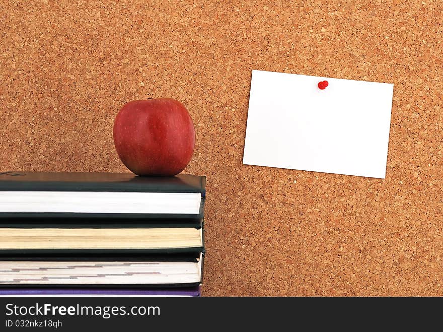 Apple and books. against the background of the inscription cork board