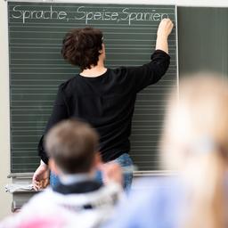 Eine Lehrerin schreibt in einer Grundschule Wörter mit «Sp» am Anfang an eine Tafel.