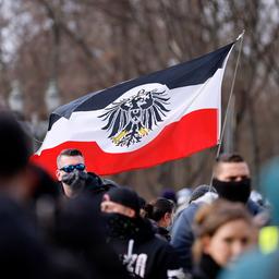 Teilnehmer auf einer Demonstration von Rechtsextremen und Reichsbürgern halten eine Fahne, die an die Reichsflagge erinnert.