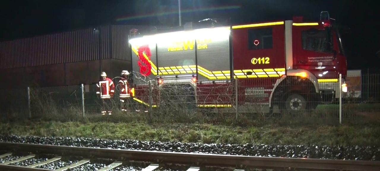 Hinter Bahngleisen steht ein Feuerwehrauto.