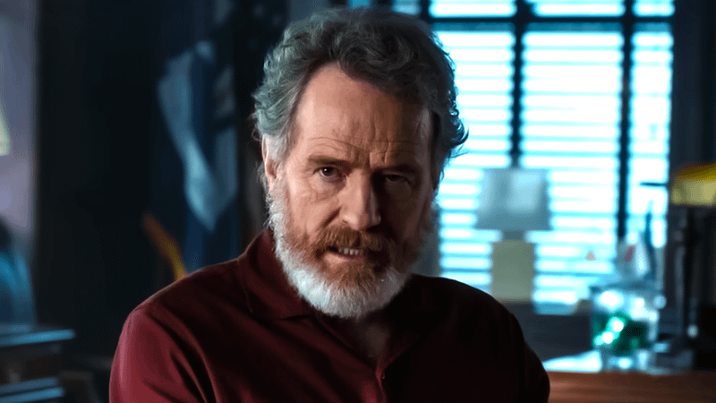Bryan Cranston with a thick white beard and a red shirt playing Michael Desiato in 