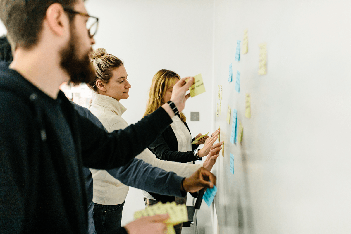 the thoughtbot, 8th light, and steel warriors team putting post-it notes 
on the whiteboard