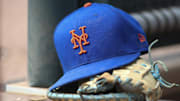 Jul 13, 2022; Atlanta, Georgia, USA; A detailed view of a New York Mets hat and glove in the dugout against the Atlanta Braves in the eighth inning at Truist Park. Mandatory Credit: Brett Davis-Imagn Images