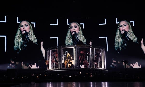 A woman sings onstage while dancers strike poses around her