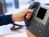 closeup of a hand on the receiver of an office phone