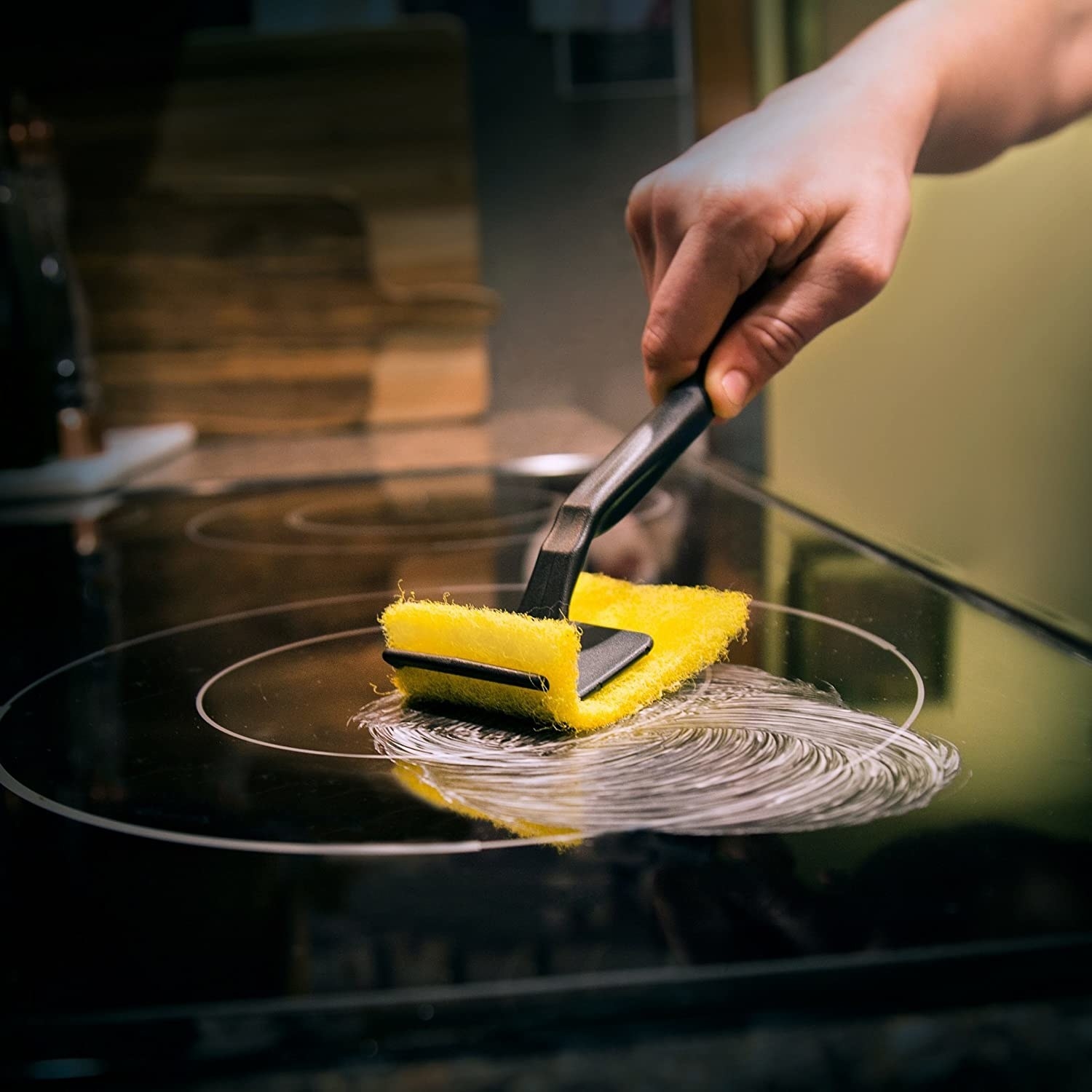 someone cleaning their stovetop with the cleaning kit