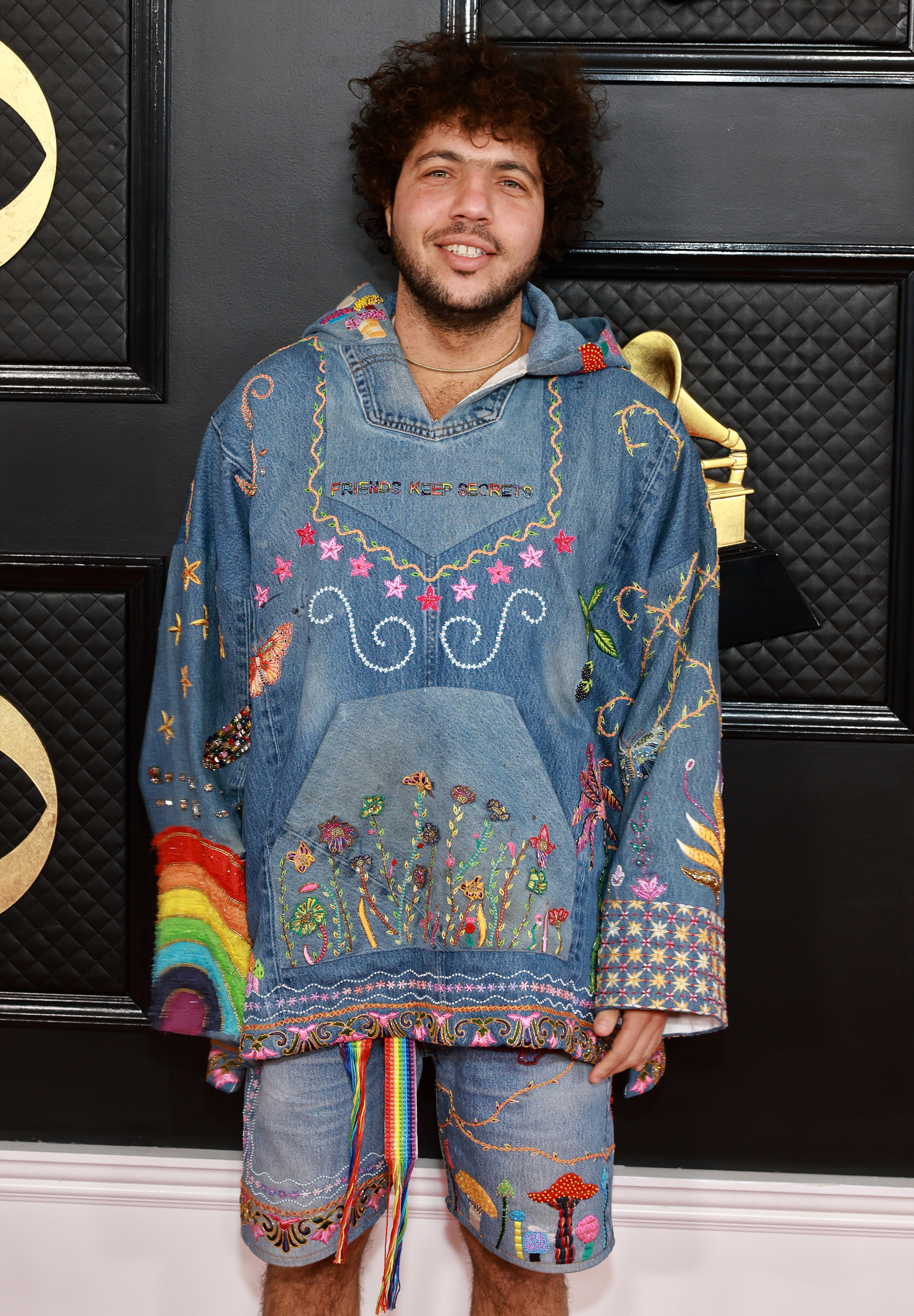 Close-up of Benny at a media event wearing an embroidered denim jacket and denim shorts