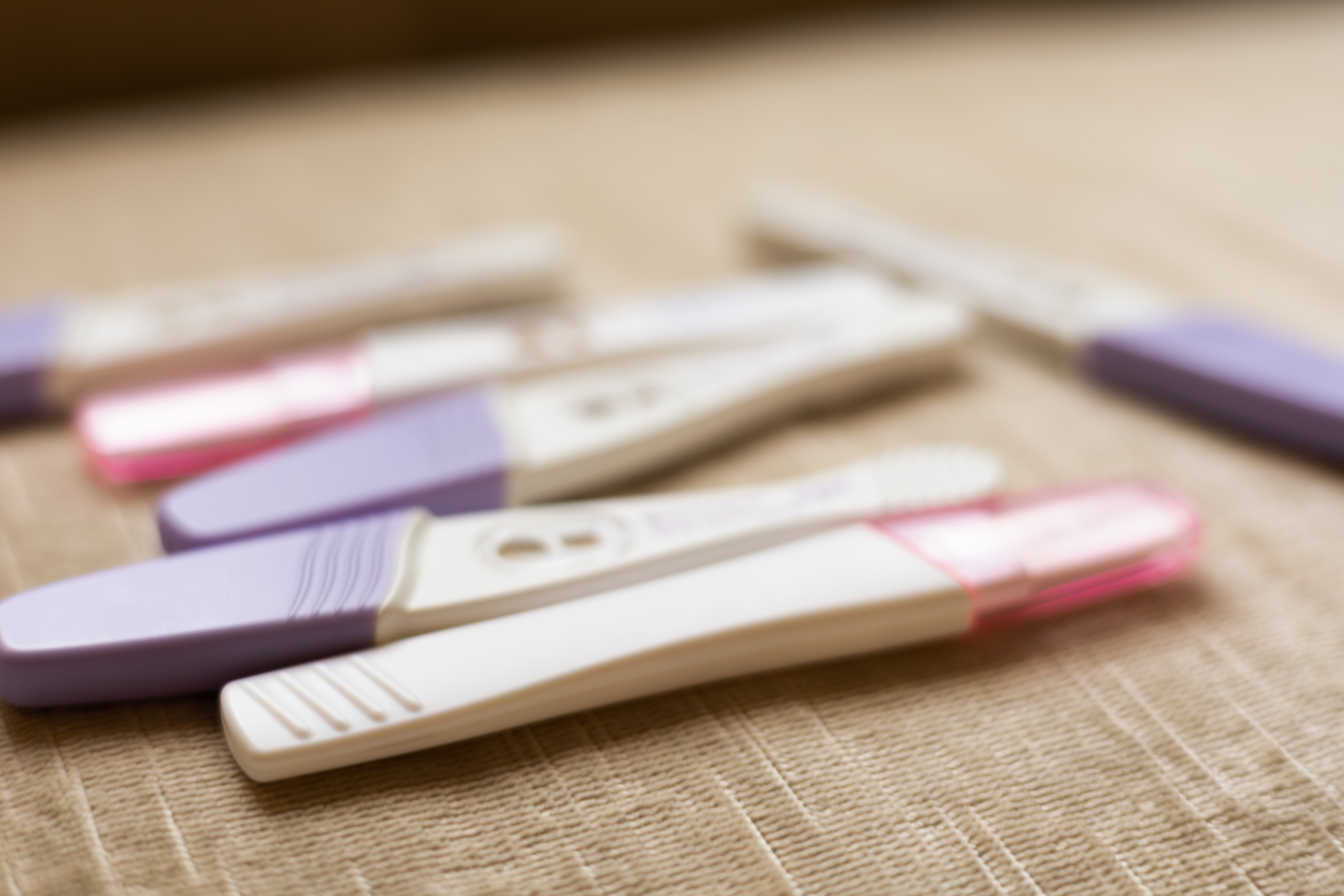 Several home pregnancy tests with different results are scattered on a surface.