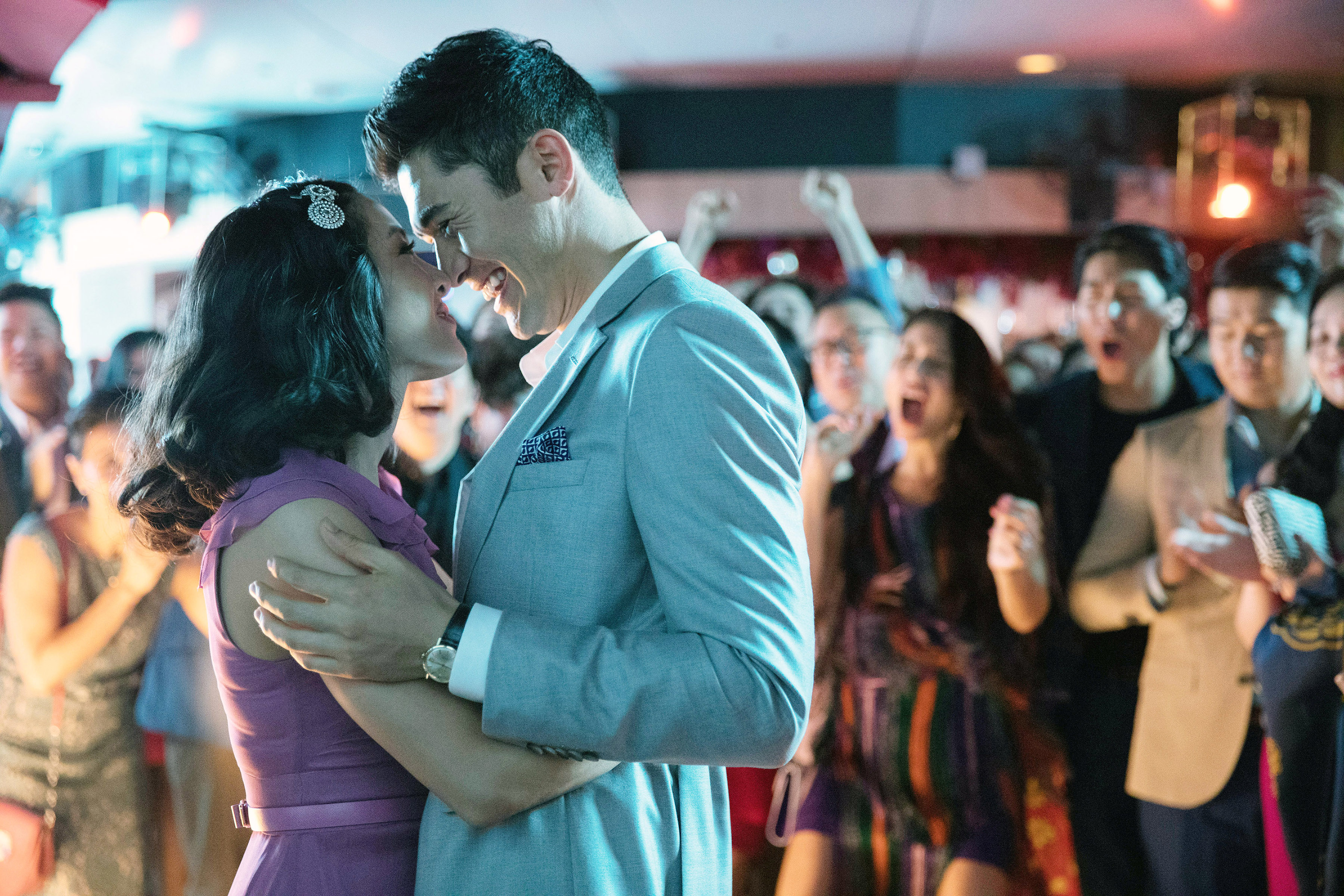 Constance Wu and Henry Golding hugging with crowds cheering them on in the background in &quot;Crazy Rich Asians.&quot;