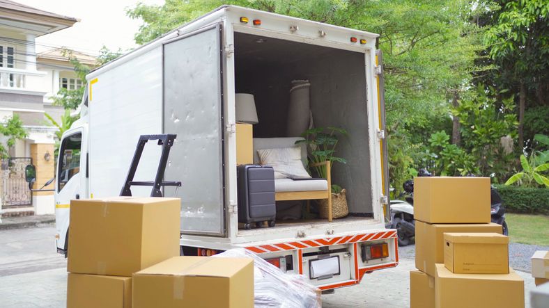 Moving truck with furniture and boxes, parked in a residential area, suggesting a move or relocation scenario