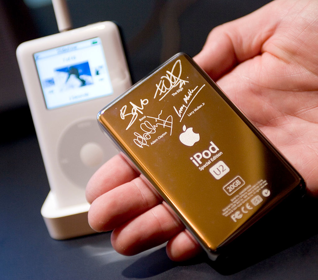 Hand holding a U2 Special Edition iPod with signatures, with a classic iPod in the background