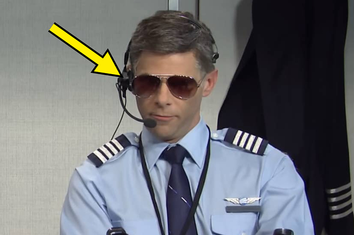 Person dressed as a pilot, wearing a headset and sunglasses, with an arrow pointing at the headset