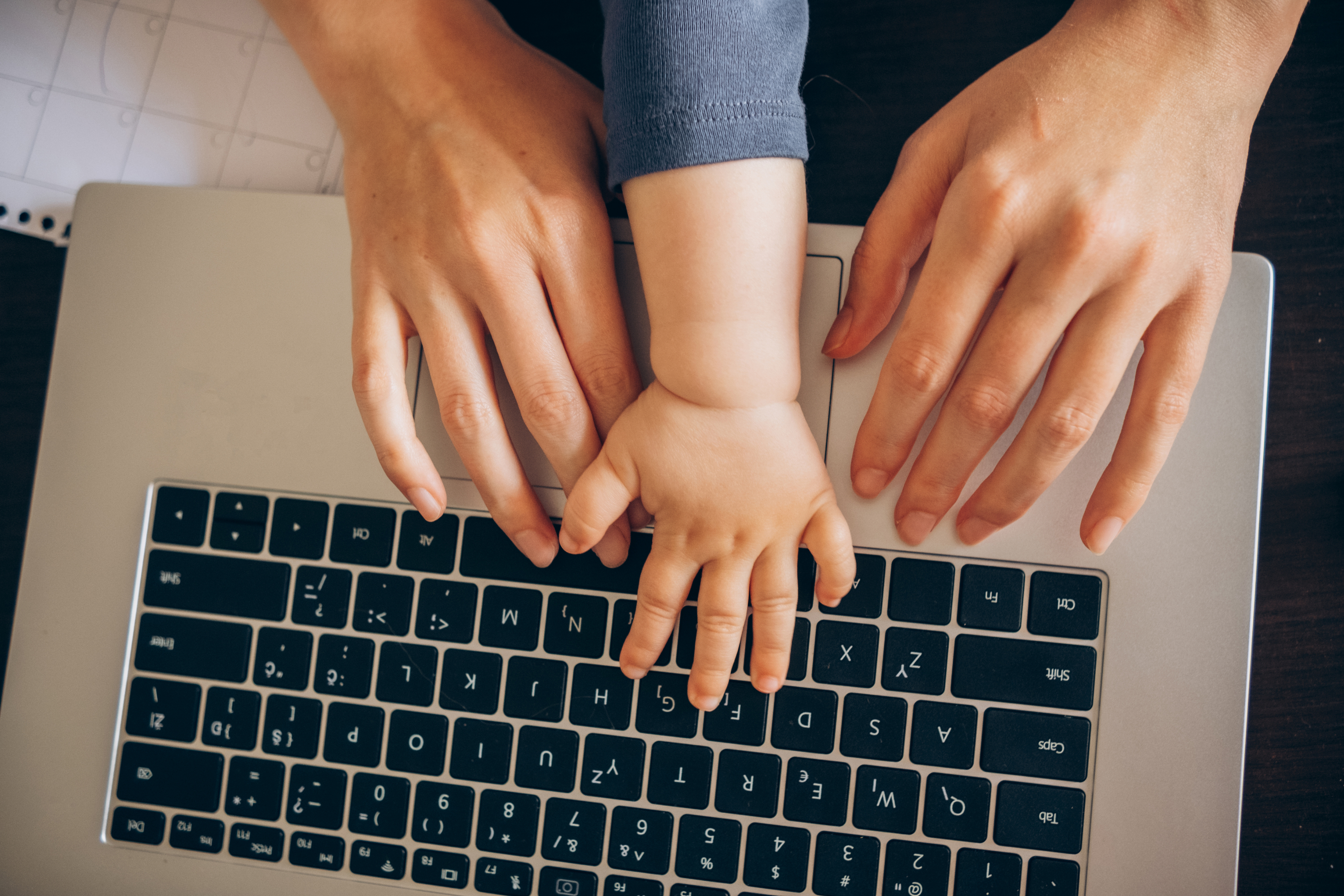 Adult and child hands on a laptop keyboard, suggesting shared technology use