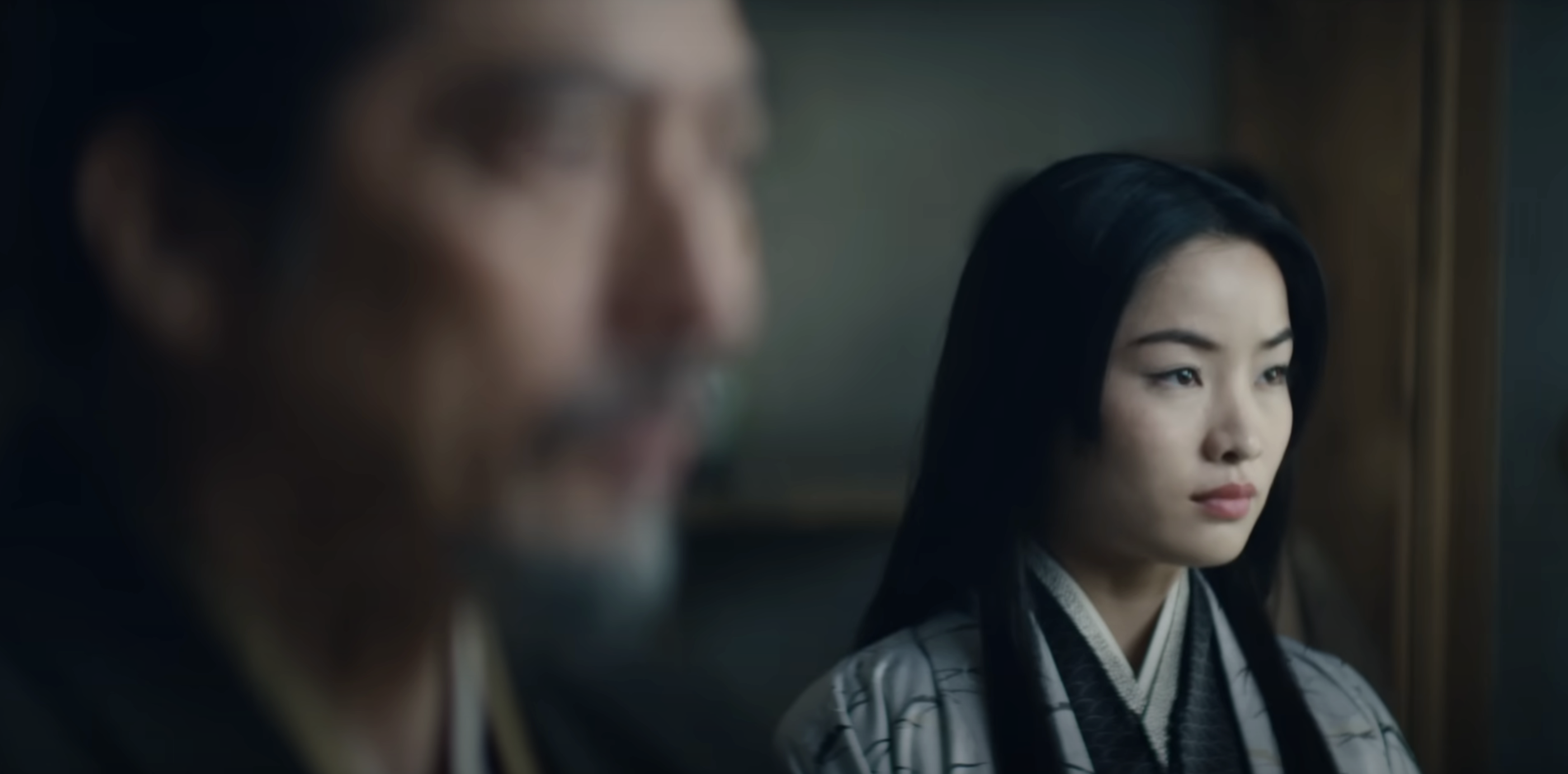 Anna Sawai in traditional attire stands in focus beside an out-of-focus Hiroyuki Sanada in the foreground