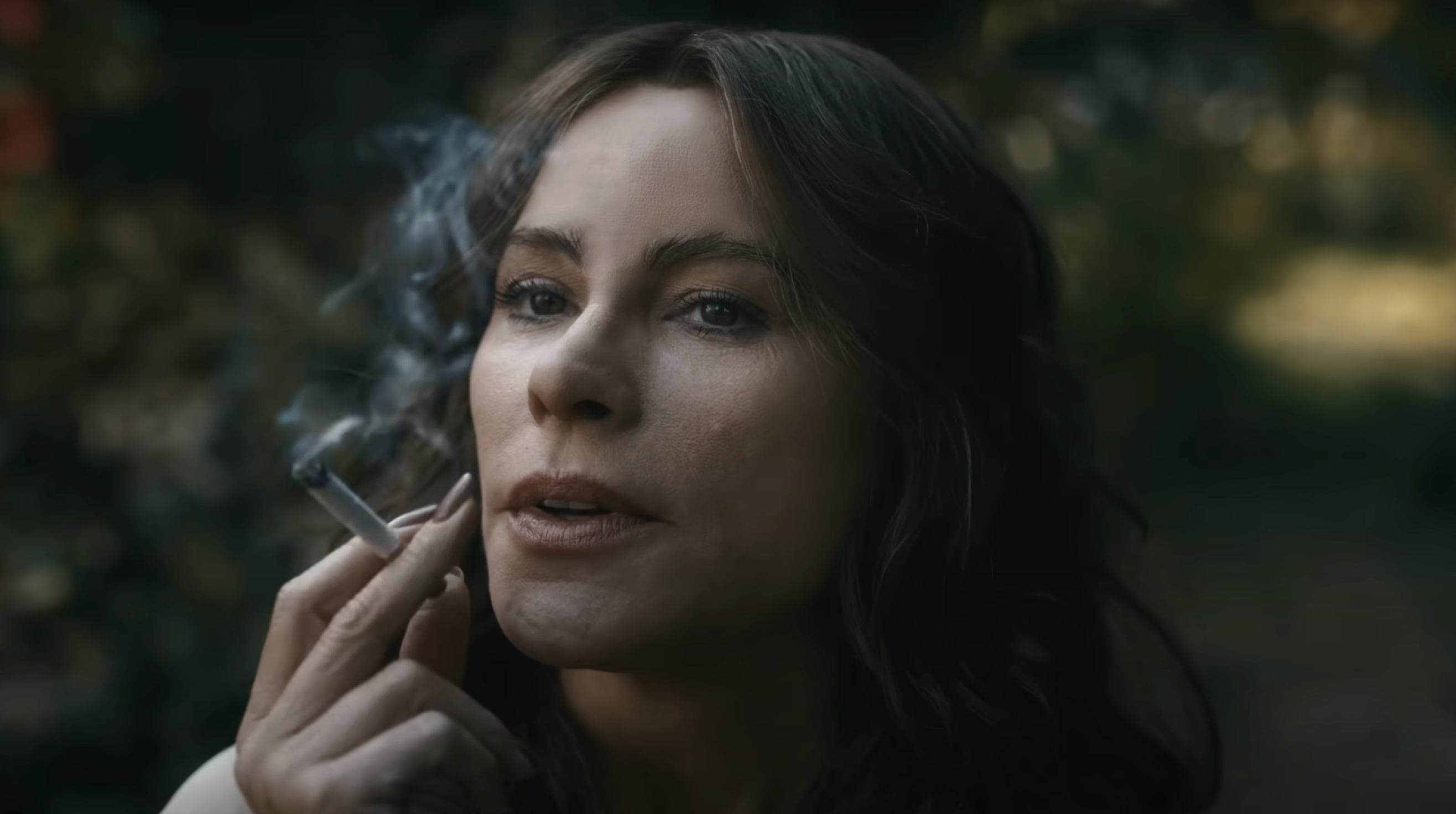 Sofía Vergara with long hair holding a smoking cigarette in a natural setting