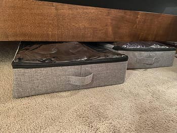 Underbed storage boxes with fabric handles neatly tucked under a bed on a carpeted floor