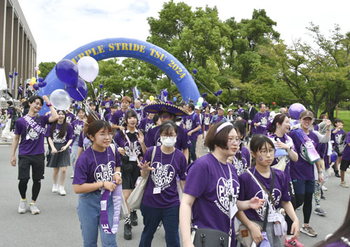 【紫色のＴシャツ姿で歩く参加者＝津市栗真町屋町の三重大で】