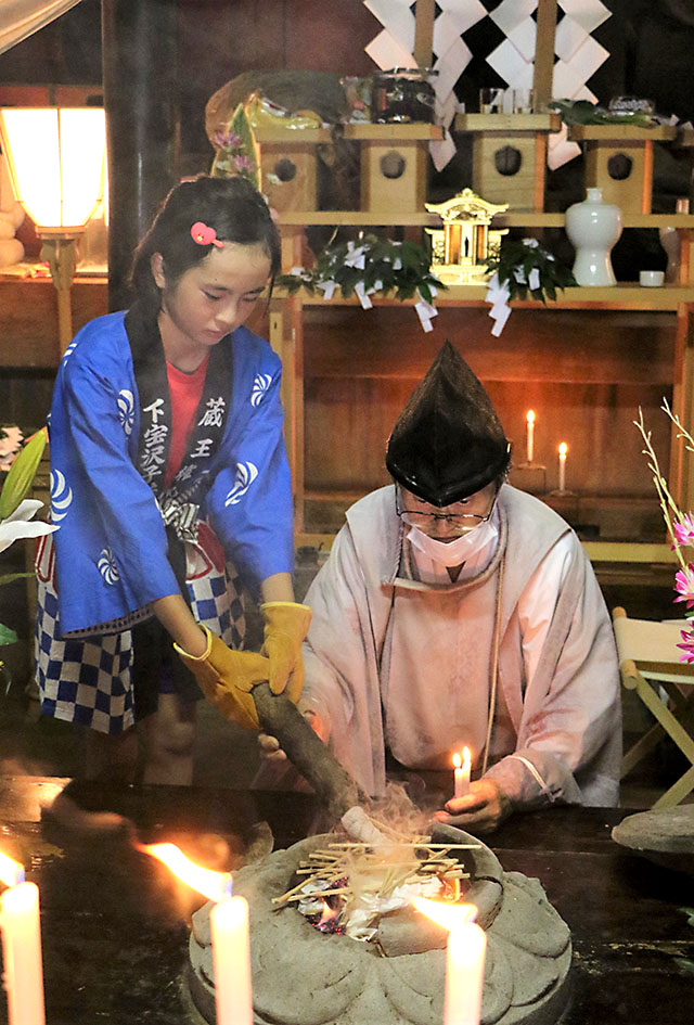 御神火をたいまつにともす横山紗恵さん＝山形市下宝沢・苅田嶺神社