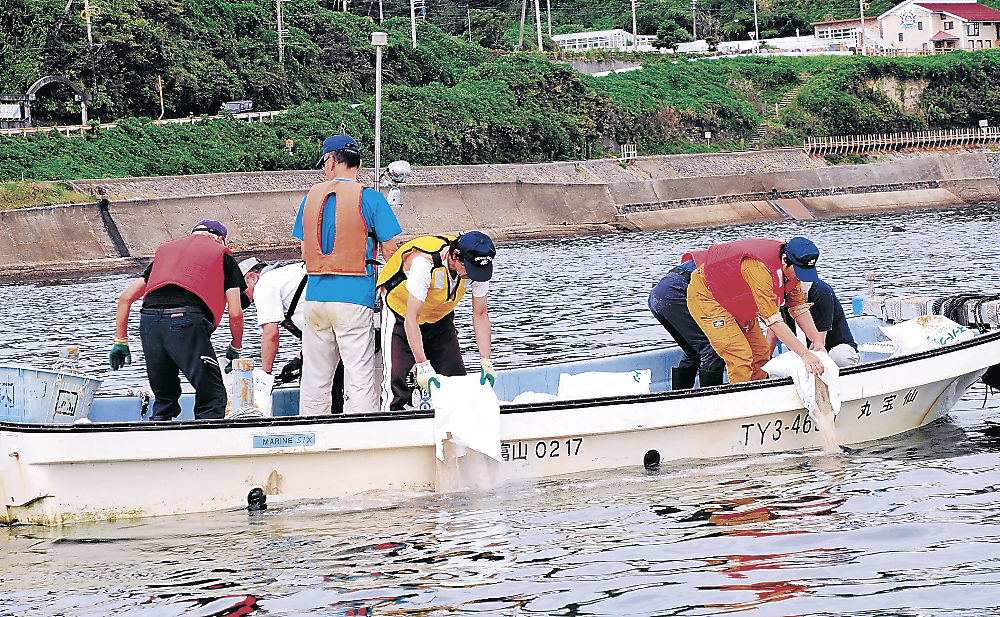 底質改良材を散布する実行組合員や住民＝高岡市の国分浜沖