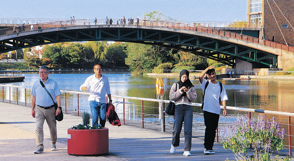 日差しが照り付ける中、半袖姿で散策する人＝富山市の富岩運河環水公園