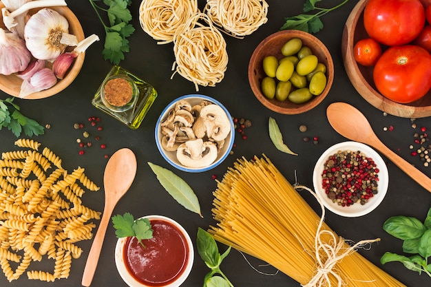 Una vista aerea di pasta cruda con ingredienti su sfondo nero