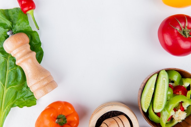 Vista del primo piano delle verdure come pomodoro di pepe con il sale di insalata di verdure e lasciare sulla tavola bianca con lo spazio della copia