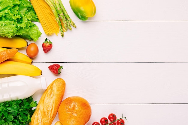 Assortimento di verdure, frutta e bottiglia di latte su fondo di legno bianco. Concetto di cibo sano vegetariano. Cibo e spesa.