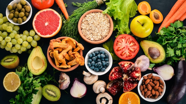 Cibo sano selezione di mangiare pulito Verdure frutta noci bacche e funghi prezzemolo spezie su sfondo nero Spazio libero per il testo