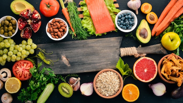 Cibo sano selezione di mangiare pulito Verdure frutta noci bacche e funghi prezzemolo spezie su sfondo nero Spazio libero per il testo