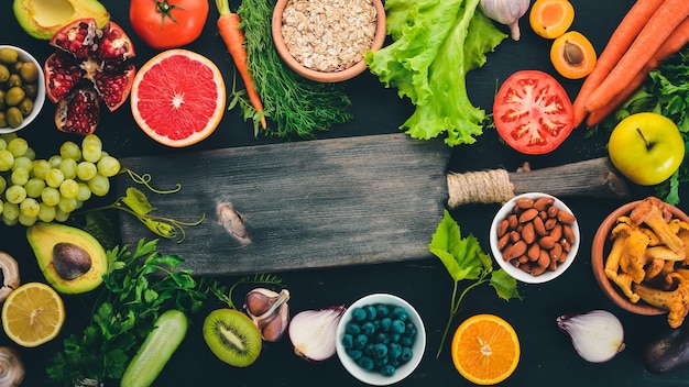 Cibo sano selezione di mangiare pulito Verdure frutta noci bacche e funghi prezzemolo spezie su sfondo nero Spazio libero per il testo