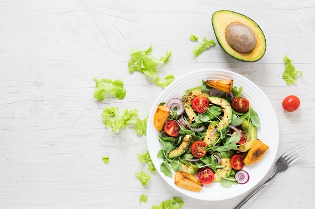 Insalata vegana con avocado sul tavolo di legno bianco