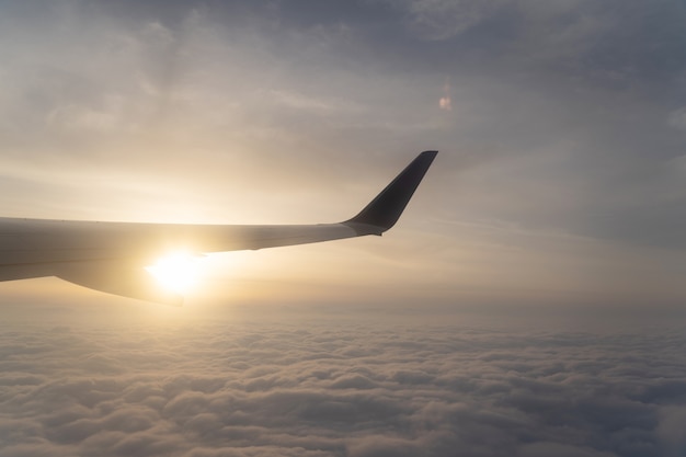 La vista del paesaggio sopra l&#39;ala dell&#39;aeroplano e della nuvola con il tramonto. Visualizza però la finestra sull&#39;aereo.