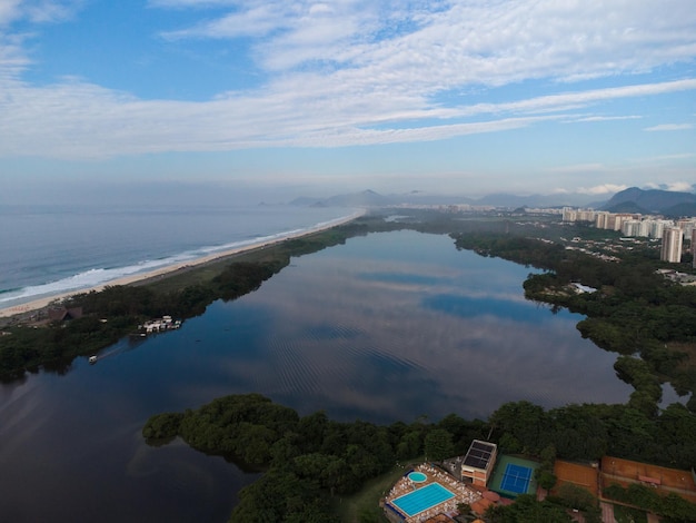 Veduta aerea della spiaggia della Reserva e della laguna di Marapendi. Sullo sfondo, le colline di Recreio dos Bandeirantes, a Rio de Janeiro, in Brasile. Alba. Giornata di sole con qualche nuvola. Foto del drone.