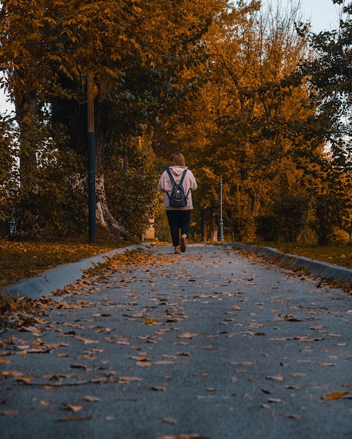 Foto gratuita vista posteriore di una giovane ragazza adolescente che cammina in un parco in una giornata autunnale