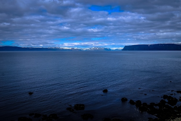 Foto gratuita bello colpo di un mare e delle montagne nella distanza sotto un cielo nuvoloso