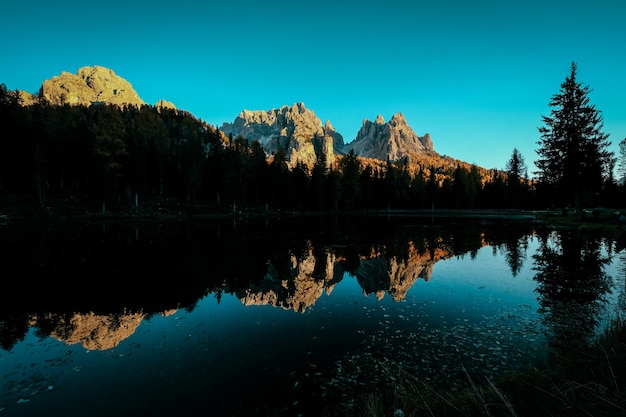 Foto gratuita bello colpo di acqua che riflette gli alberi e le montagne con cielo blu