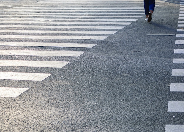 Foto gratuita bella ripresa delle strisce pedonali sulla strada con la donna che ci cammina sopra