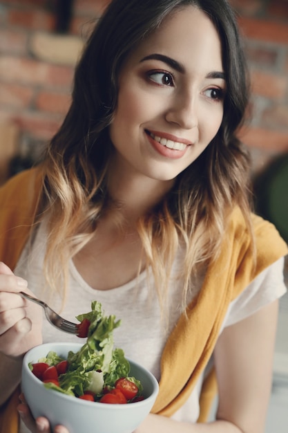 Foto gratuita bella giovane donna che mangia un'insalata sana