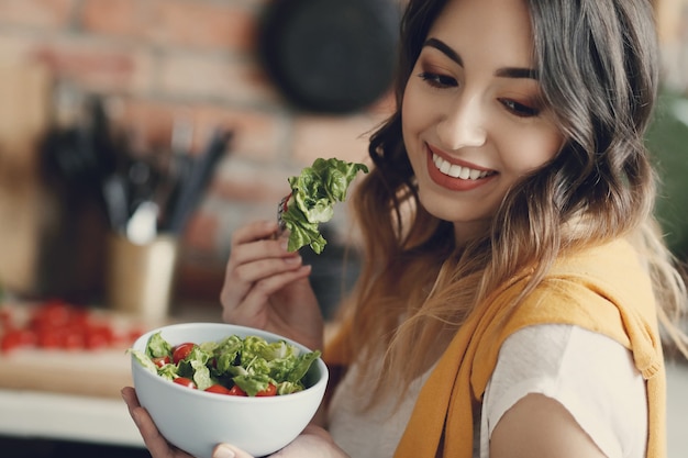 Foto gratuita bella giovane donna che mangia un'insalata sana